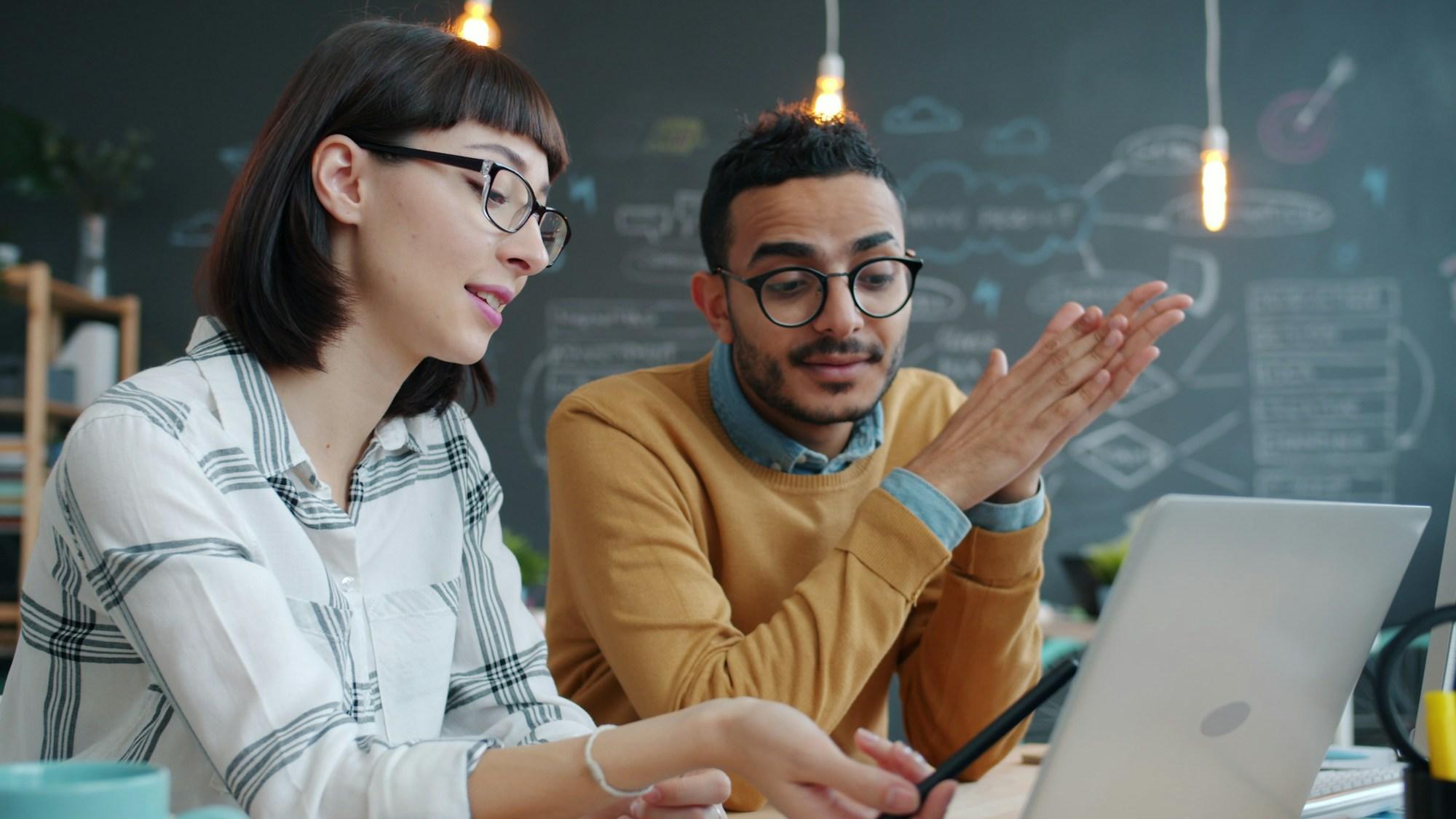 Colleagues reviewing work together on a laptop